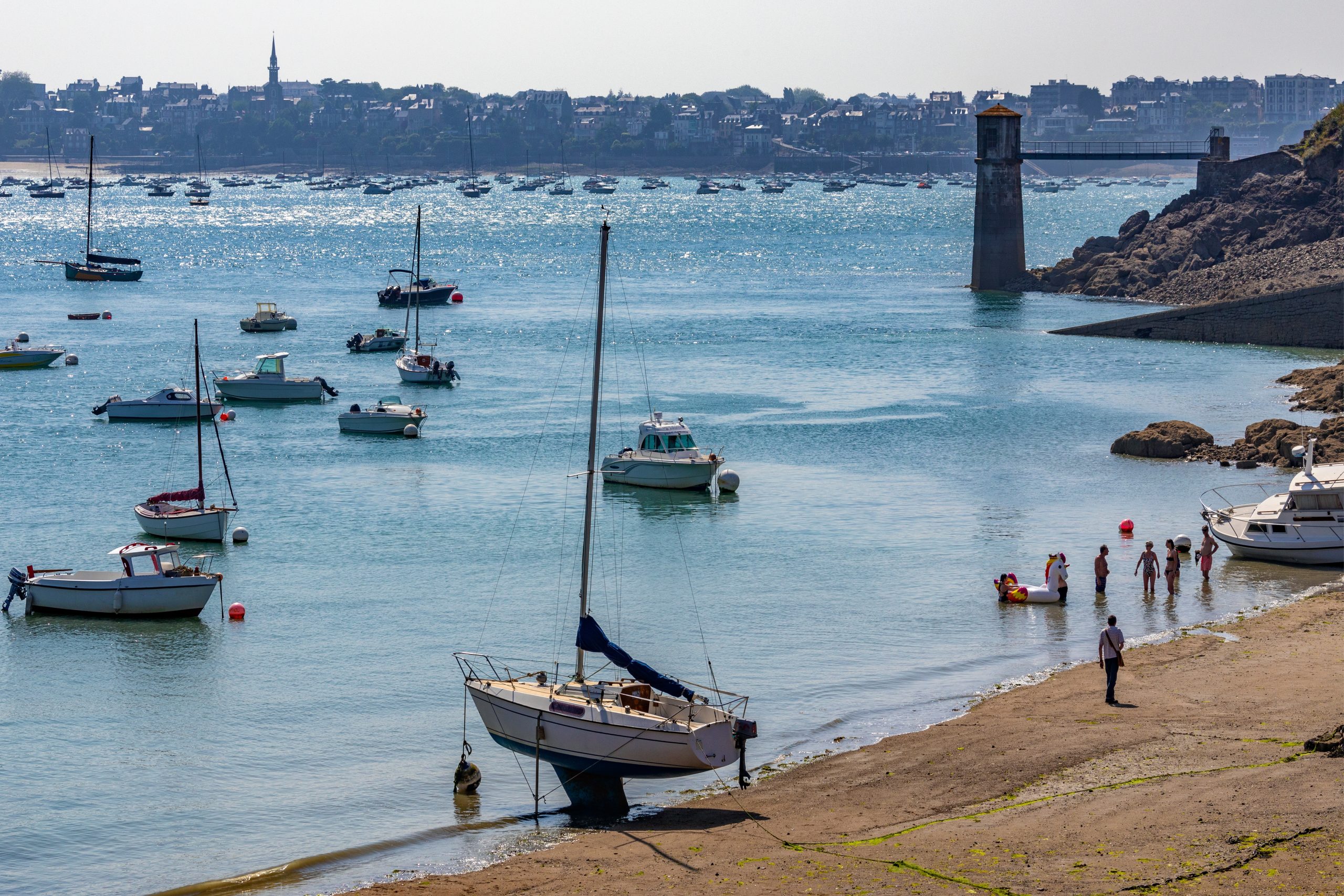 Plage de Dinard avec voiliers et couples au bord de l’eau, idéale pour un week-end romantique en Bretagne